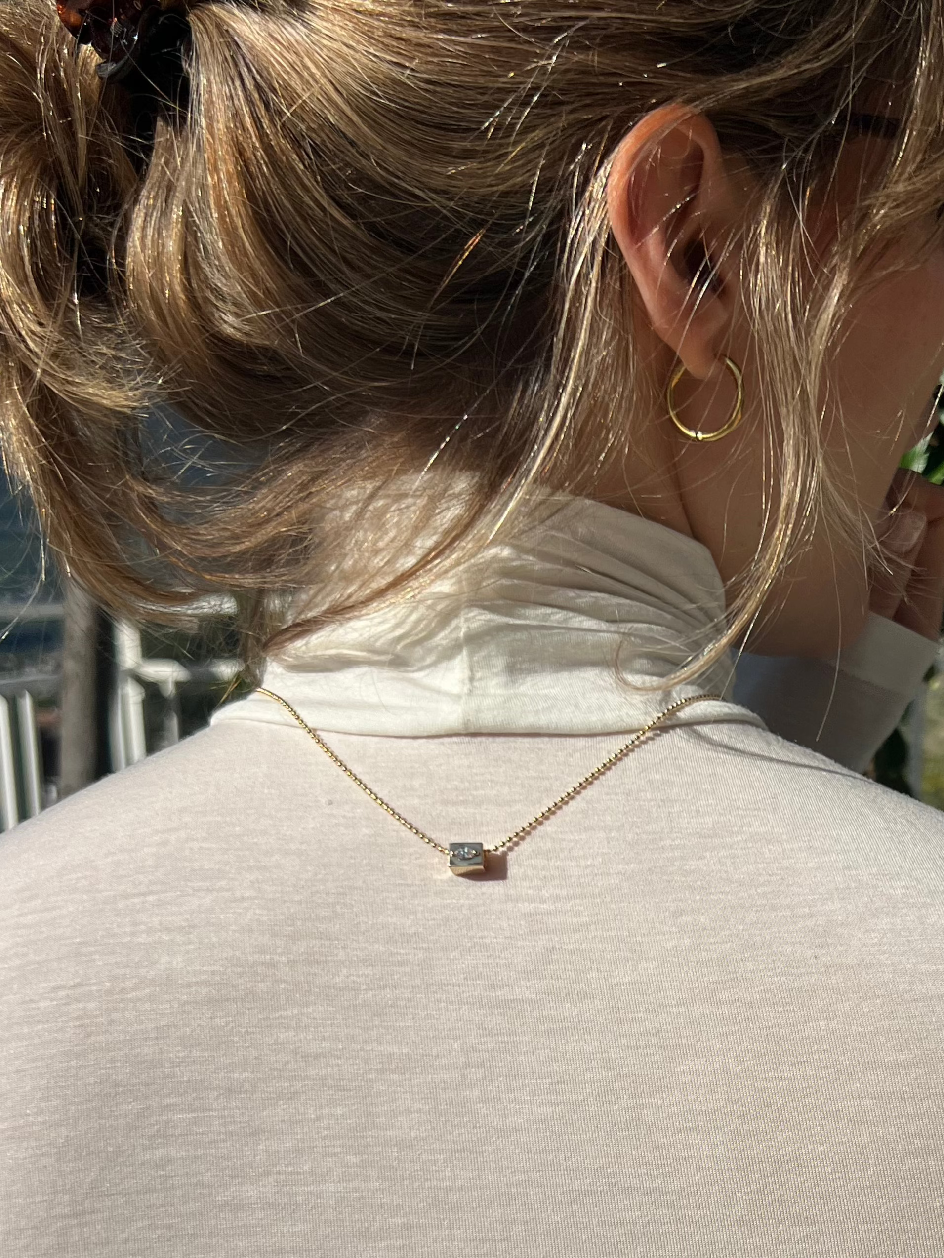 old chain with marquise stone pendant elegantly placed on a white textured surface, showcasing playful elegance and sparkle.